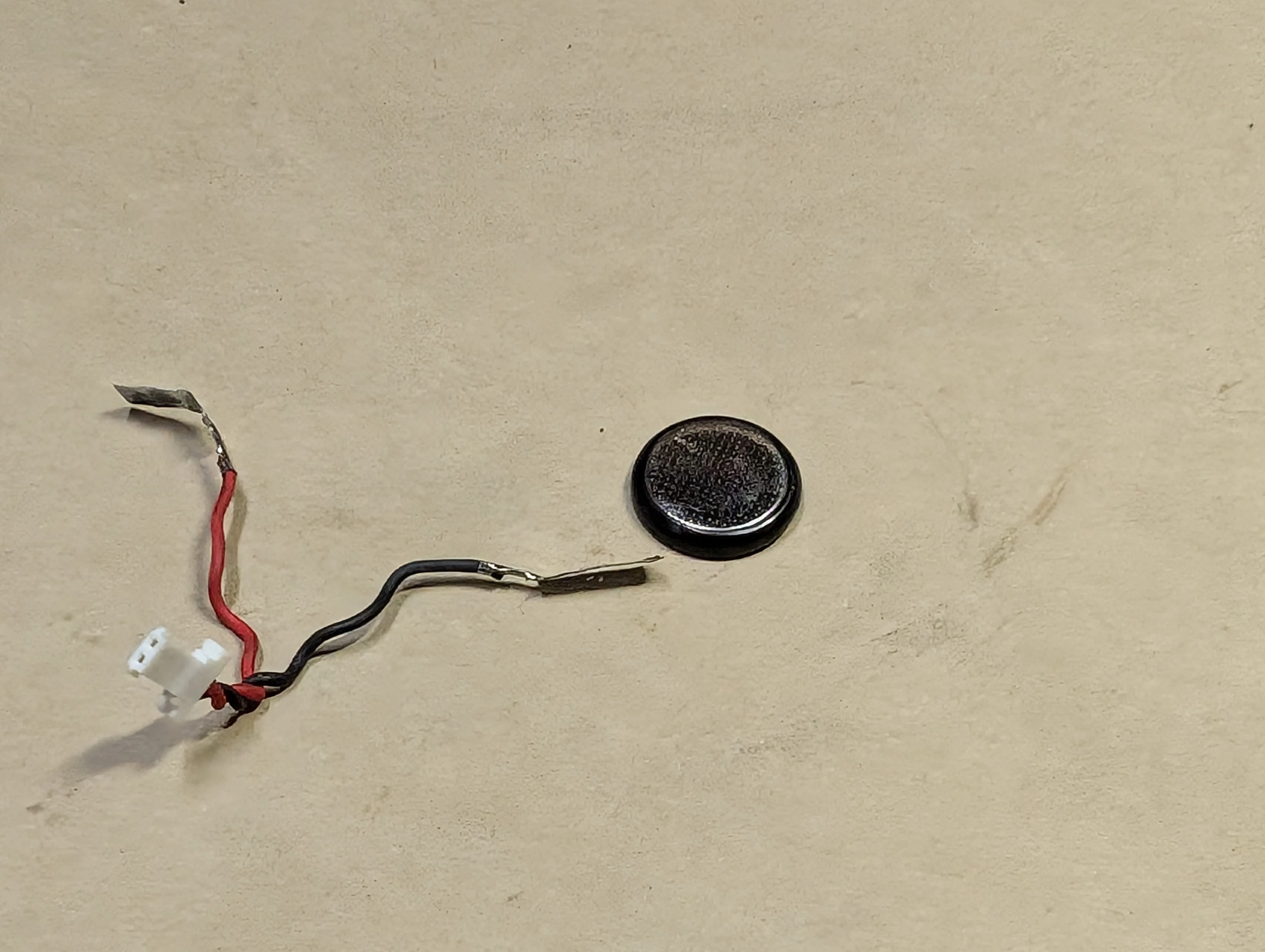 The RTC battery with its positive and negative contacts separated from the cell